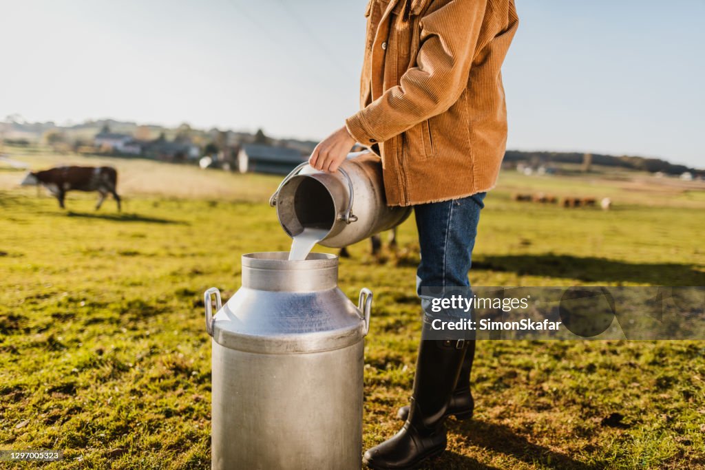 Female Farmer pouring raw milk into container