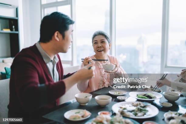 aziatische chinese mens die reüniediner met haar moeder tijdens chinese nieuwe jaarviering thuis heeft - 65 year old asian women stockfoto's en -beelden