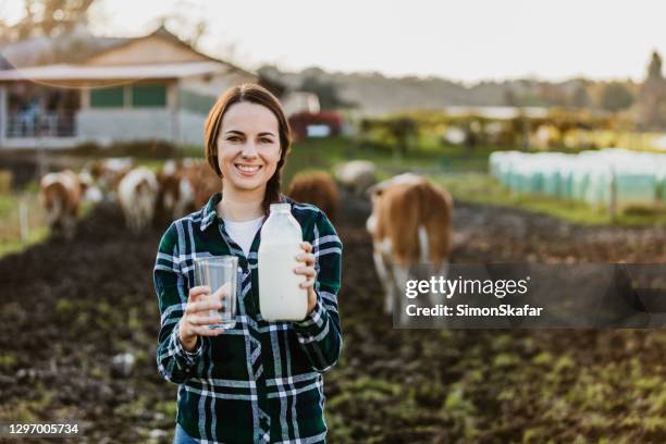 jeune bouteille de lait de fixation de femme avec le verre sur le laitier - fermier lait photos et images de collection