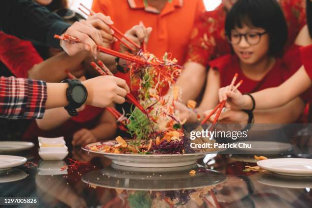 asiatische mehrgenerationen-chinesische familie feiert chinesischen silvester mit traditionellen gerichten rohen fisch lau sang yee sang während des wiedersehens abendessen - traditional festival stock-fotos und bilder