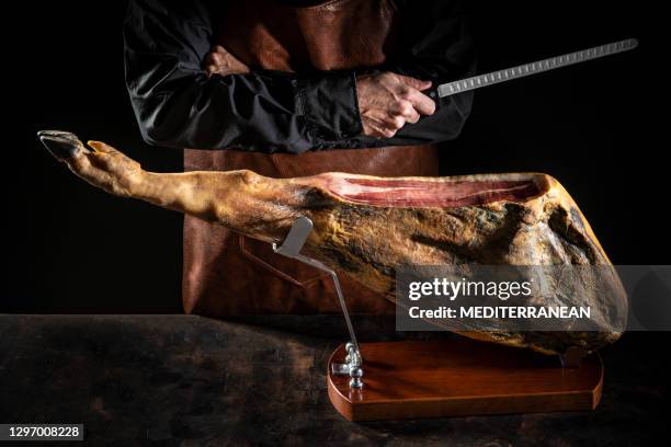 iberian ham serrano ham male butcher holding knife on dark moody background - serrano ham stock pictures, royalty-free photos & images