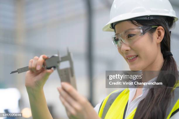 expert female engineer use vernier caliper measuring workpiece at factory - schieblehre stock-fotos und bilder