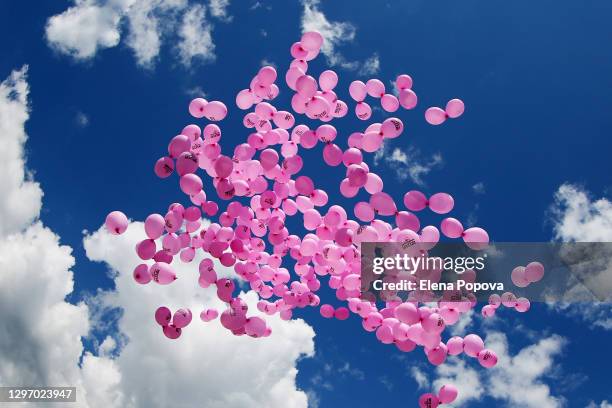 a bunch of pink helium balloons in the blue sky - groep fietsers stockfoto's en -beelden