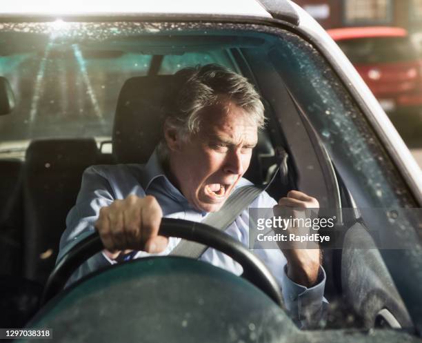 man shakes his fist and shouts in road rage as he drives a car - road rage stock pictures, royalty-free photos & images