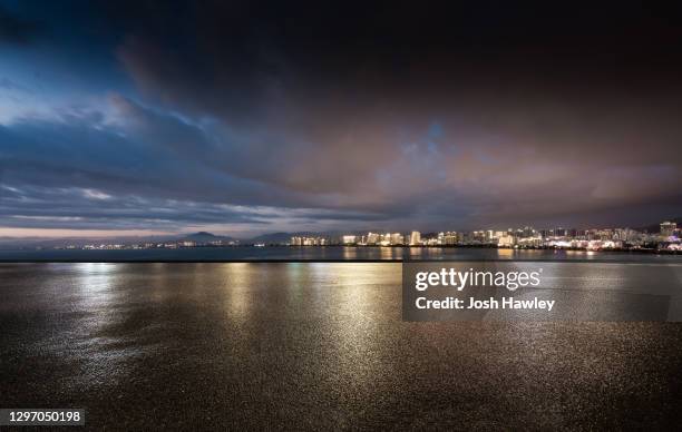 empty parking lot with cityscape background - night at the net stockfoto's en -beelden