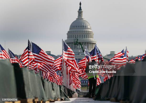Aaron Haines helps place American flags on the National Mall as the U.S Capitol Building is prepared for the inaugural ceremonies for President-elect...