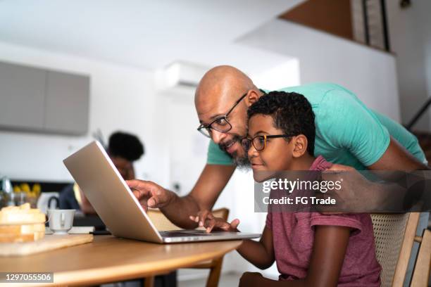 father encouraging son on homeschooling or doing a video call/watching a movie - kid school supplies stock pictures, royalty-free photos & images