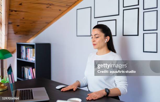 relajada y tranquila mujer de negocios tomar profundo aliento de aire fresco descansando con los ojos cerrados en el trabajo en la oficina en casa. hacer yoga de oficina y meditar con los ojos cerrados. - respiratory fotografías e imágenes de stock