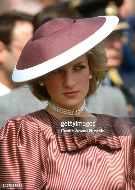 Diana, Princess of Wales, wearing a maroon striped dress with a bow designed by Catherine Walker and a flying saucer style hat designed by Frederick...