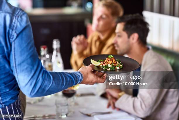 waiter serving plate of food to customers - servicio de calidad fotografías e imágenes de stock