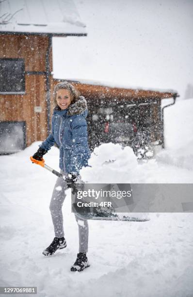 frau räumt bei starkem schneefall die vorfahrt - snow shovel stock-fotos und bilder