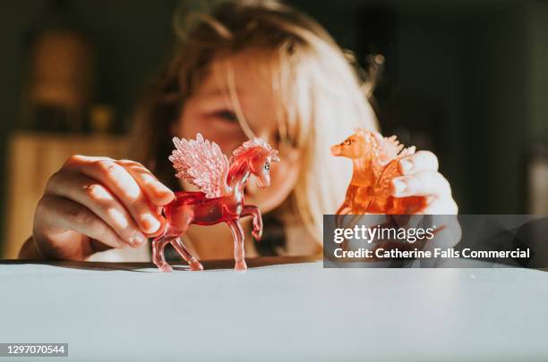 little girl holds two plastic unicorns on a soft surface - stereotipo sessuale foto e immagini stock