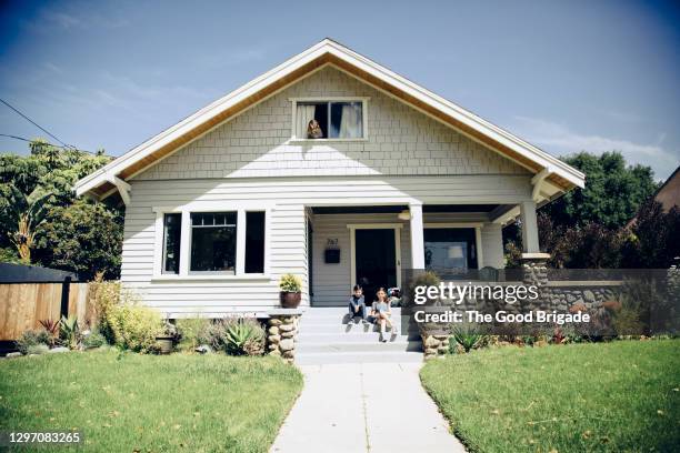 brother and sister sitting on front step at home on sunny day - exterior house fotografías e imágenes de stock