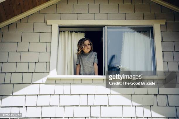 boy looking out bedroom window at home - front view bildbanksfoton och bilder