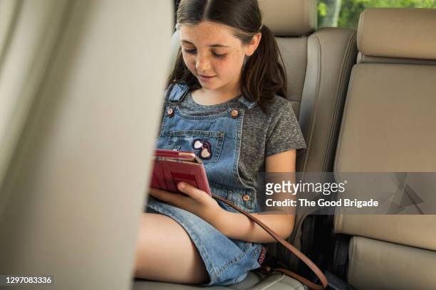 girl using digital tablet in car - girl in car with ipad stock pictures, royalty-free photos & images