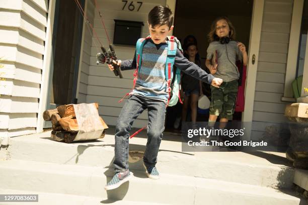 boy with fishing pole jumping off front steps at home - step brother stock pictures, royalty-free photos & images