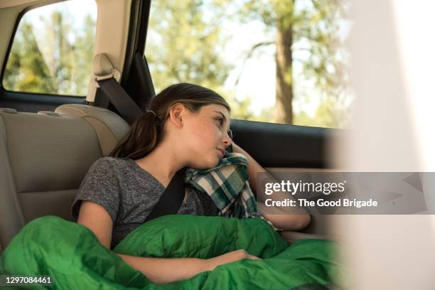 sad girl looking through window while sitting in car - filles voiture photos et images de collection