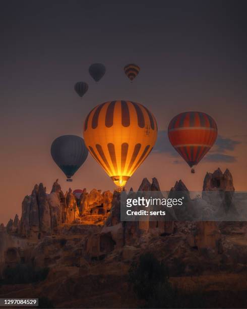 hot air balloons flying over rock formations at sunrise in cappadocia, goreme, turkey - hot air balloon imagens e fotografias de stock