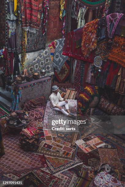 jovem turista masculino curtindo na tradicional loja de tapetes na capadócia, turquia - persian culture - fotografias e filmes do acervo