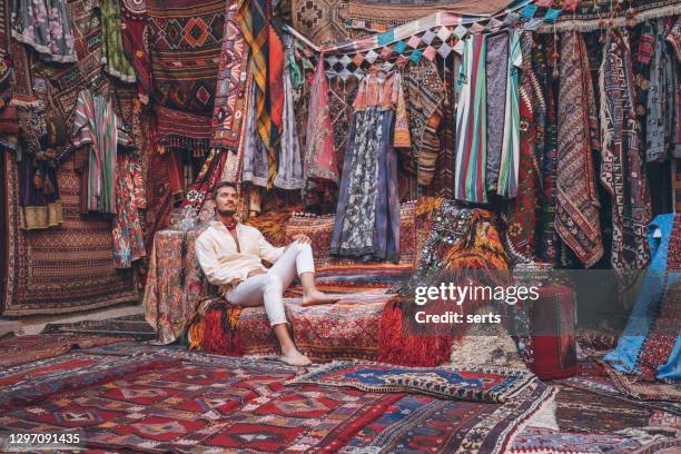 young male tourist enjoying at traditional carpet shop in cappadocia, turkey - man throne stock pictures, royalty-free photos & images