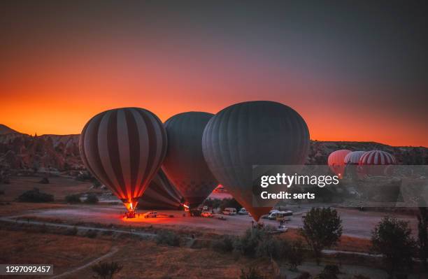 hot air balloons flying over rock formations at sunrise in cappadocia, goreme, turkey - cave fire stock pictures, royalty-free photos & images