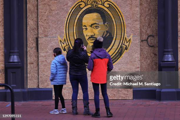 People stop to look at a Martin Luther King Jr poster on MLK Jr Day on January 18, 2021 in Washington, DC. Due to the coronavirus pandemic no formal...