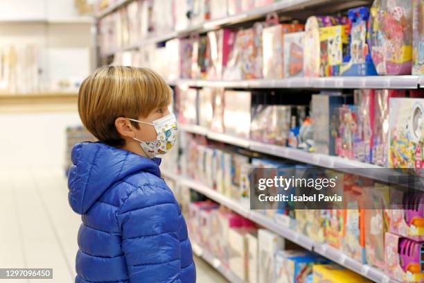 boy with face mask at toy store - loja de brinquedos imagens e fotografias de stock