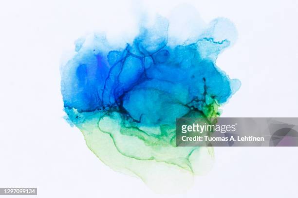 close-up of abstract blue and green alcohol ink texture on white. - blue watercolor stock pictures, royalty-free photos & images