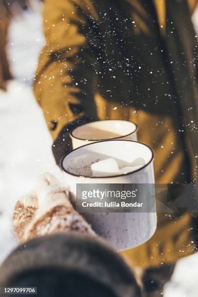 man and woman hands in knitting mittens with cups of hot tea on winter forest glade - woman hands in mittens stock-fotos und bilder