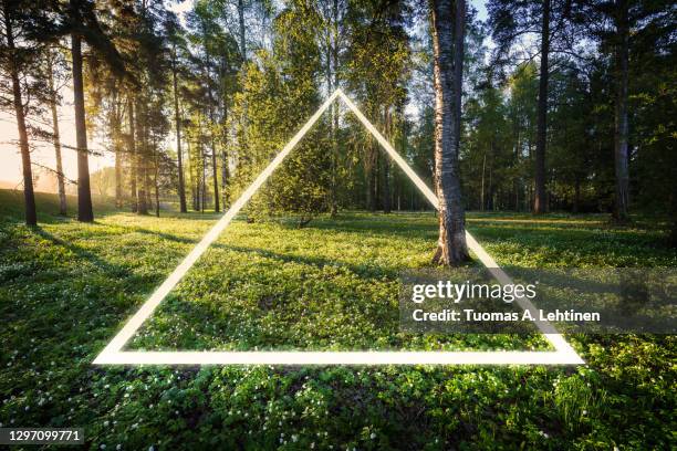 futuristic, bright, glowing neon lighting triangle at lush greenspace and meadow at sunrise in the summertime. - tampere bildbanksfoton och bilder