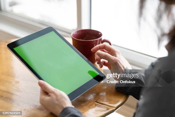 plan rapproché des mains de femme retenant la tablette numérique d’écran vert de clé de chroma dans le bureau - personne ipad main bureau photos et images de collection