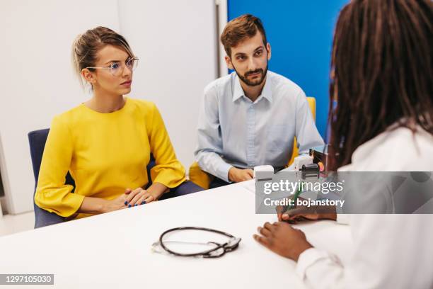 young couple at doctor's office - infertility doctor stock pictures, royalty-free photos & images