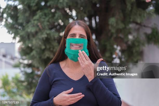 profesor de lenguaje de señas feliz usando máscara facial transparente y diciendo "gracias" en asl en el patio trasero - american sign language fotografías e imágenes de stock