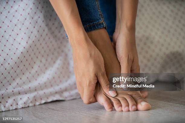 lage sectie van jonge vrouw die haar voet masseert - his foot stockfoto's en -beelden