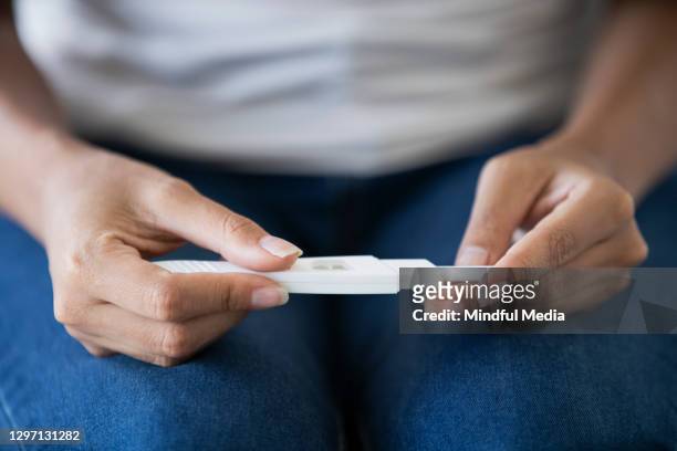 mid section of young woman holding pregnancy test - pregnancy test stock pictures, royalty-free photos & images