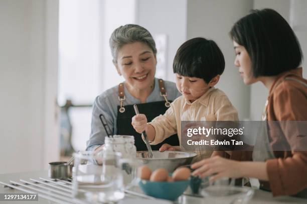 asiatische chinesische mehrgenerationenfamilie bereitet essen mit mehlbacken an küchentheke zusammen - asian granny pics stock-fotos und bilder