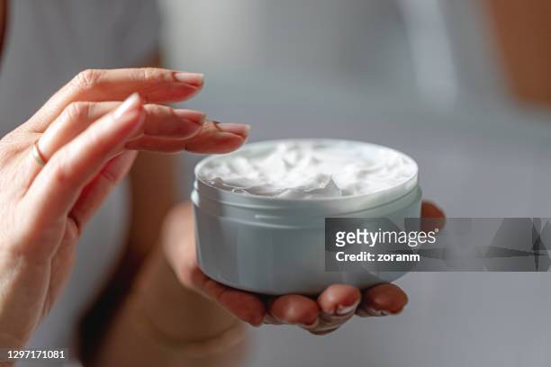 woman using moisturizing cream for clean and soft skin - cosmetic jar imagens e fotografias de stock