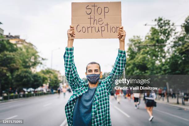 young man with a face mask and a poster in his hands about bitcoin. young activist / protester. blockchain activist - holding poster stock pictures, royalty-free photos & images