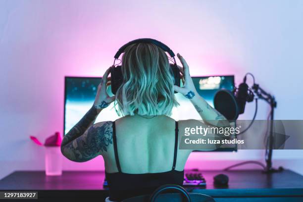 weibliche spielerin setzt ihre kopfhörer auf - video game stock-fotos und bilder