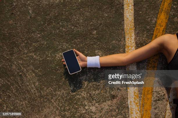 mano de una deportista sosteniendo un smartphone con una pantalla en blanco (copiar espacio) - cinta deportiva del pelo fotografías e imágenes de stock