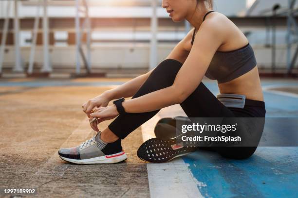 morning workouts: anonymous fit woman runner tying shoelaces on sneakers - tieing shoelace stock pictures, royalty-free photos & images