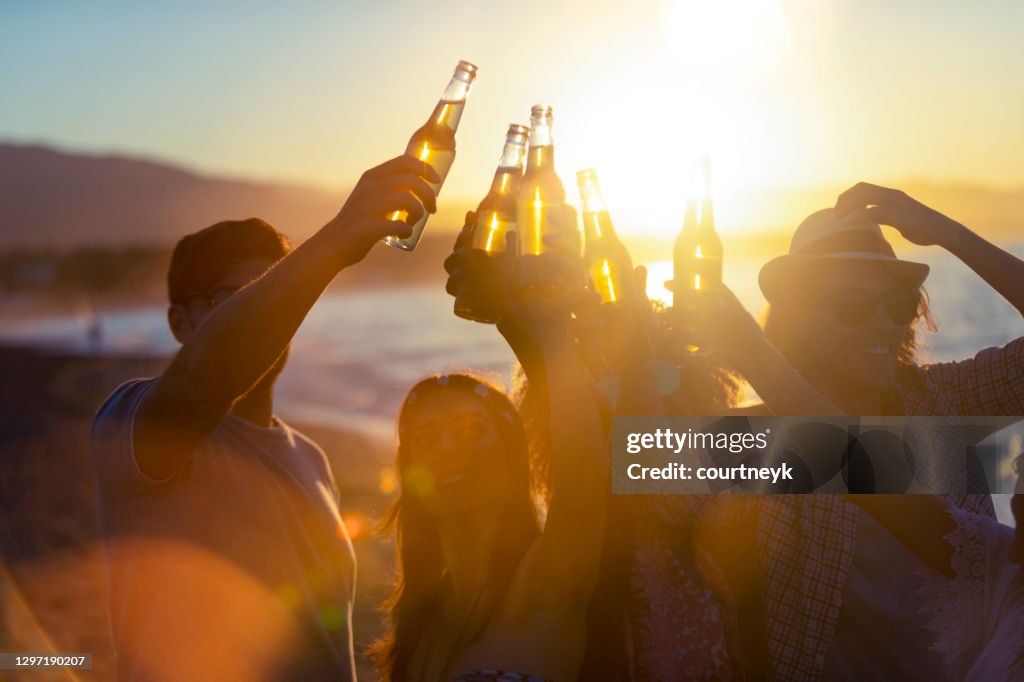 日没時にビーチでパーティーをする若者のグループ。