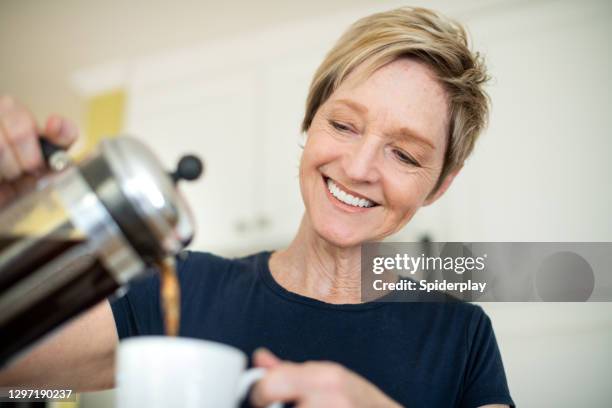 smiling older woman pouring her coffee - coffee plunger stock pictures, royalty-free photos & images