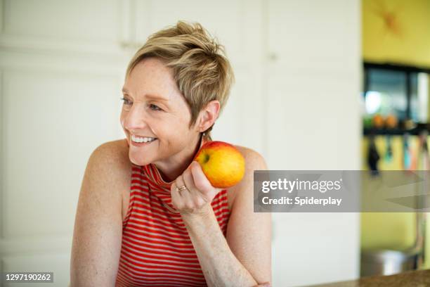 smiling stylish woman eating an apple - implante imagens e fotografias de stock