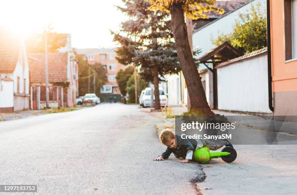 boy fall down while riding motorcycle around the neighborhood - 4 wheel motorbike stock pictures, royalty-free photos & images