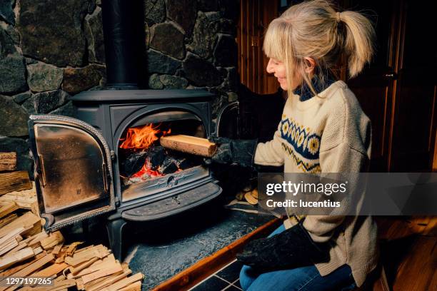 wood burning stove - stoking stock pictures, royalty-free photos & images