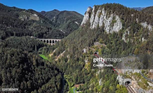 aerial panorama of red train rides on historical semmering railway (semmeringbahn) and famous kalte rinne viaduct, lower austria. - semmering austria stock pictures, royalty-free photos & images