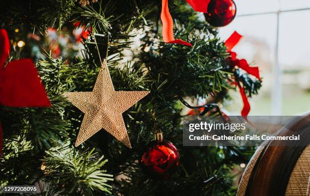 beautiful gold christmas star hanging on a christmas tree - decoración navideña fotografías e imágenes de stock