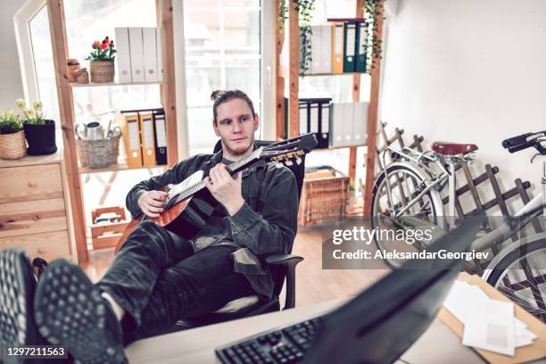 mannetje dat een onderbreking neemt die gitaar speelt terwijl het werken in bureau - heavy metal stockfoto's en -beelden