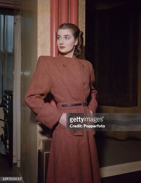 Female fashion model Moira Howard wears a light brown Rensor diagonal belted tweed coat with shoulder pads and large cuffs in London in 1947.